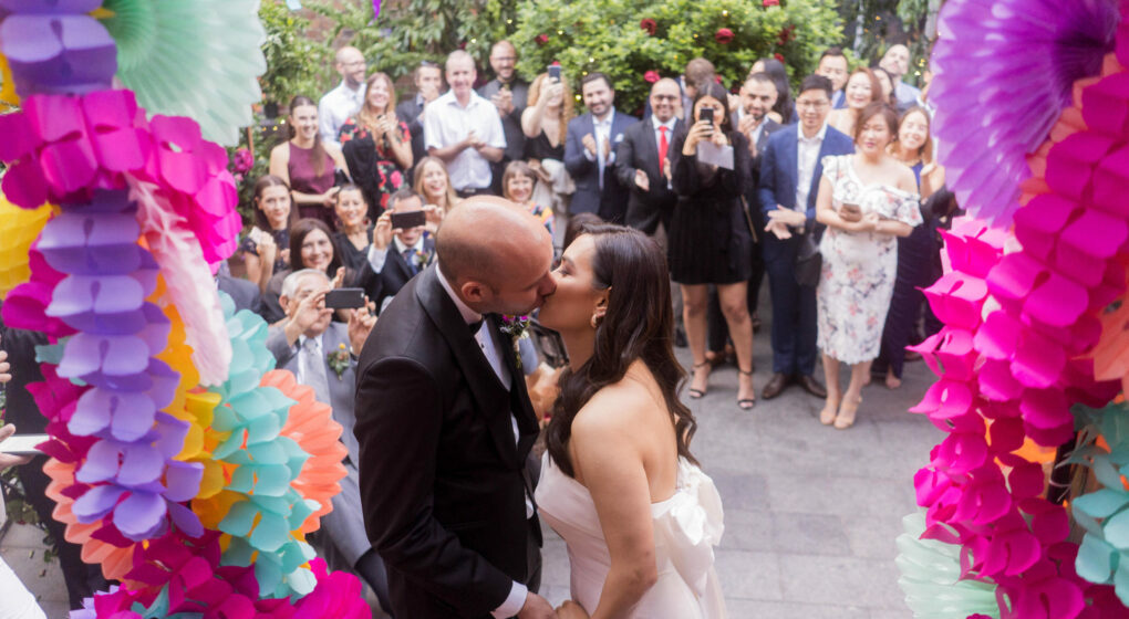 Married couple kissing under wedding arch